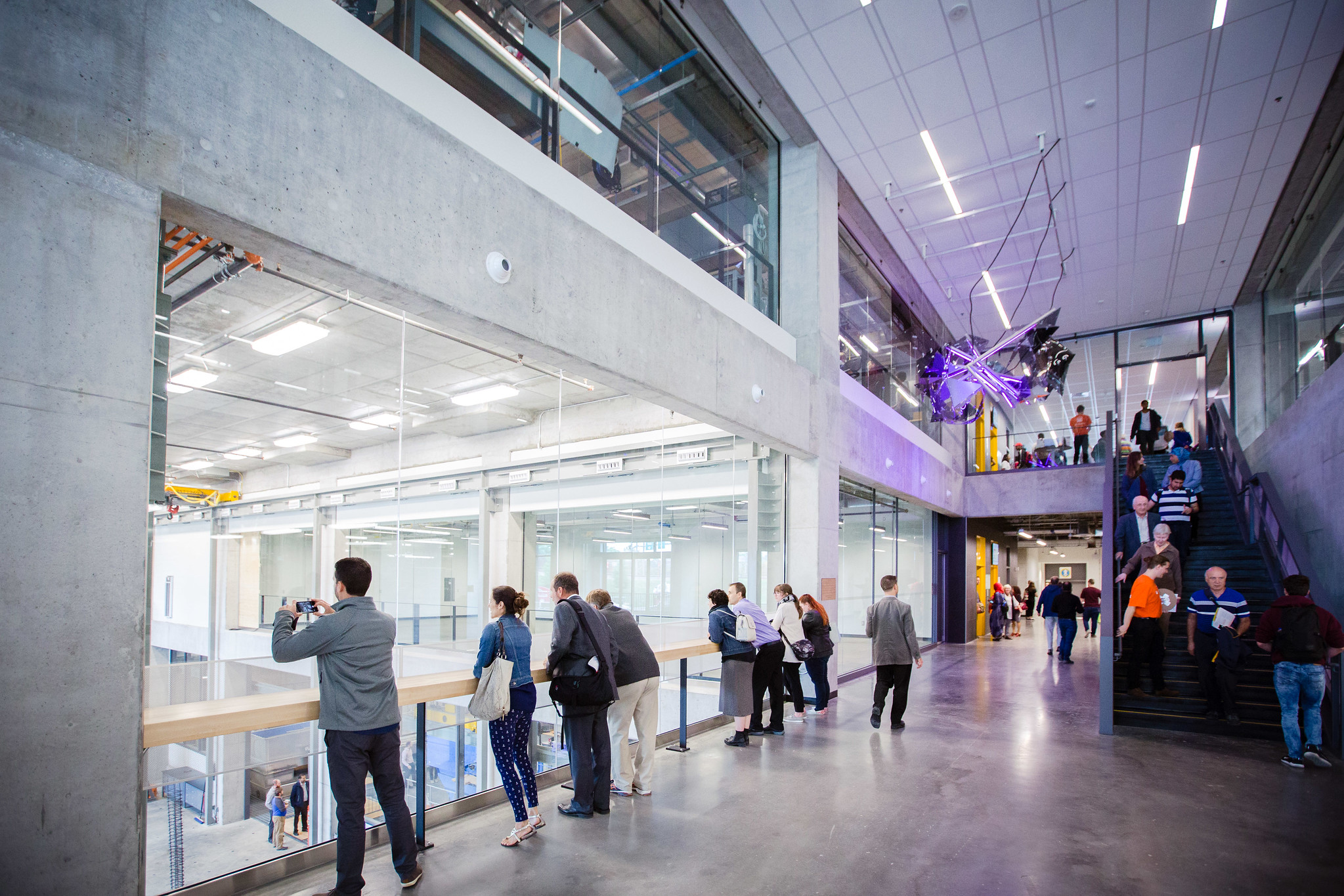 Large entrance hall with people looking inside rooms through windows 