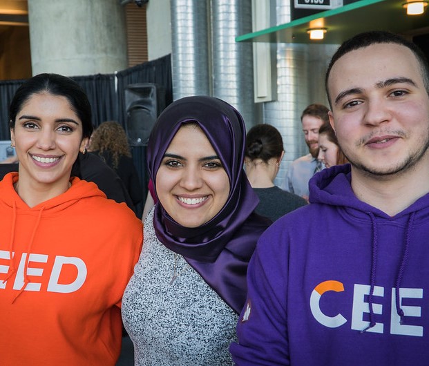 Three CEED employees smiling while wearing CEED hoodies